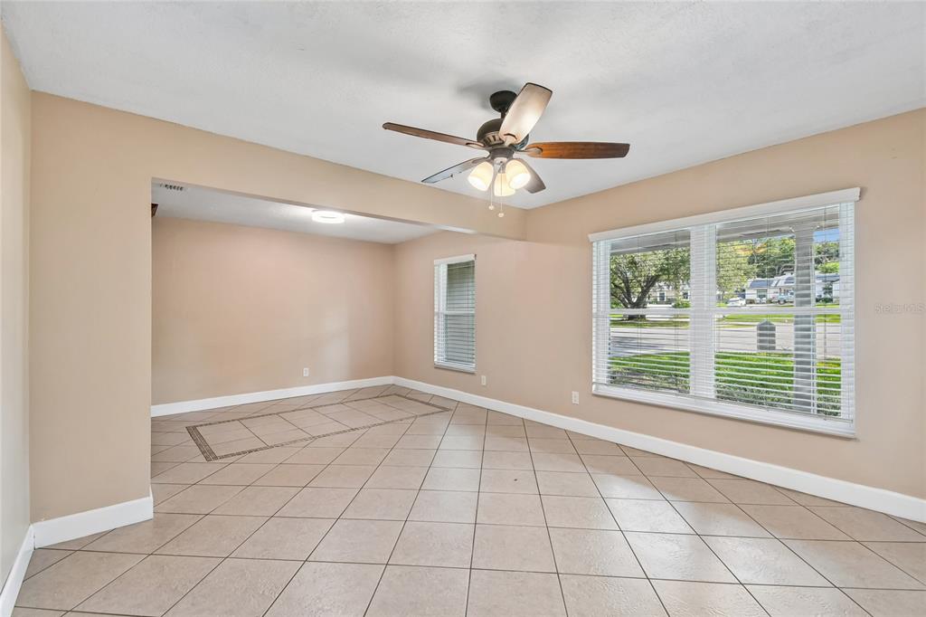 An empty room with beige walls, tile flooring, a ceiling fan, and large windows — 3244 HUNTER COURT, APOPKA, FL