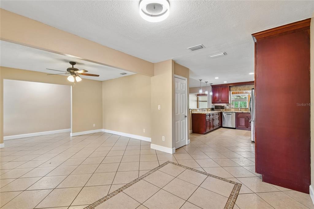 An open-concept living area with tile floors leads into a kitchen with dark wood cabinets — 3244 HUNTER COURT, APOPKA, FL