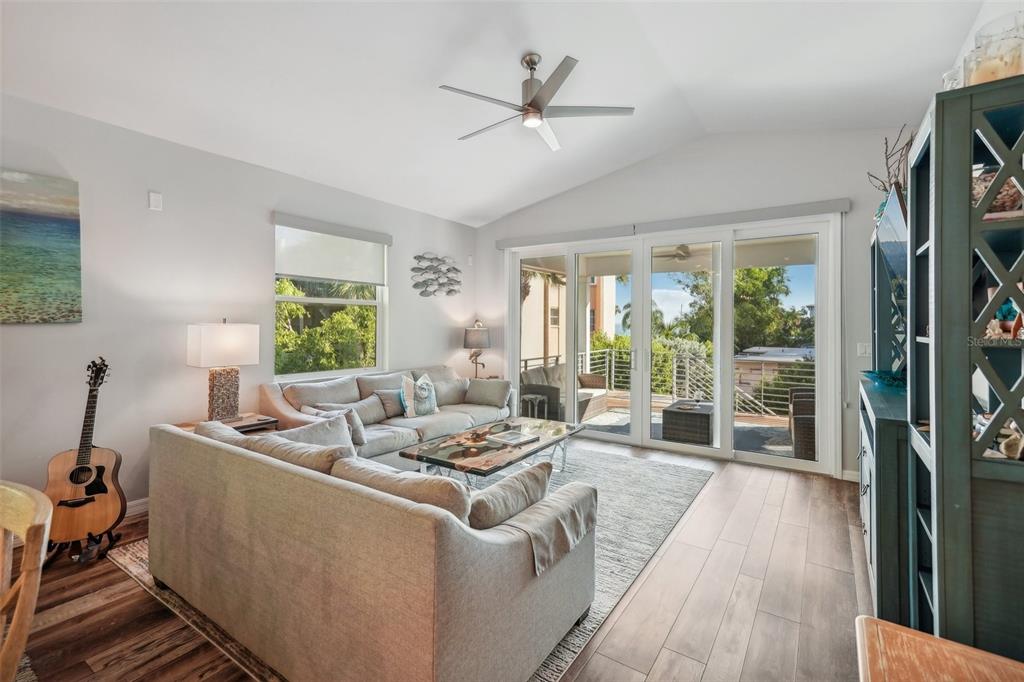 A living room features a sectional sofa, a coffee table, a ceiling fan, and sliding doors — 501 CHANNEL LANE, LONGBOAT KEY, FL