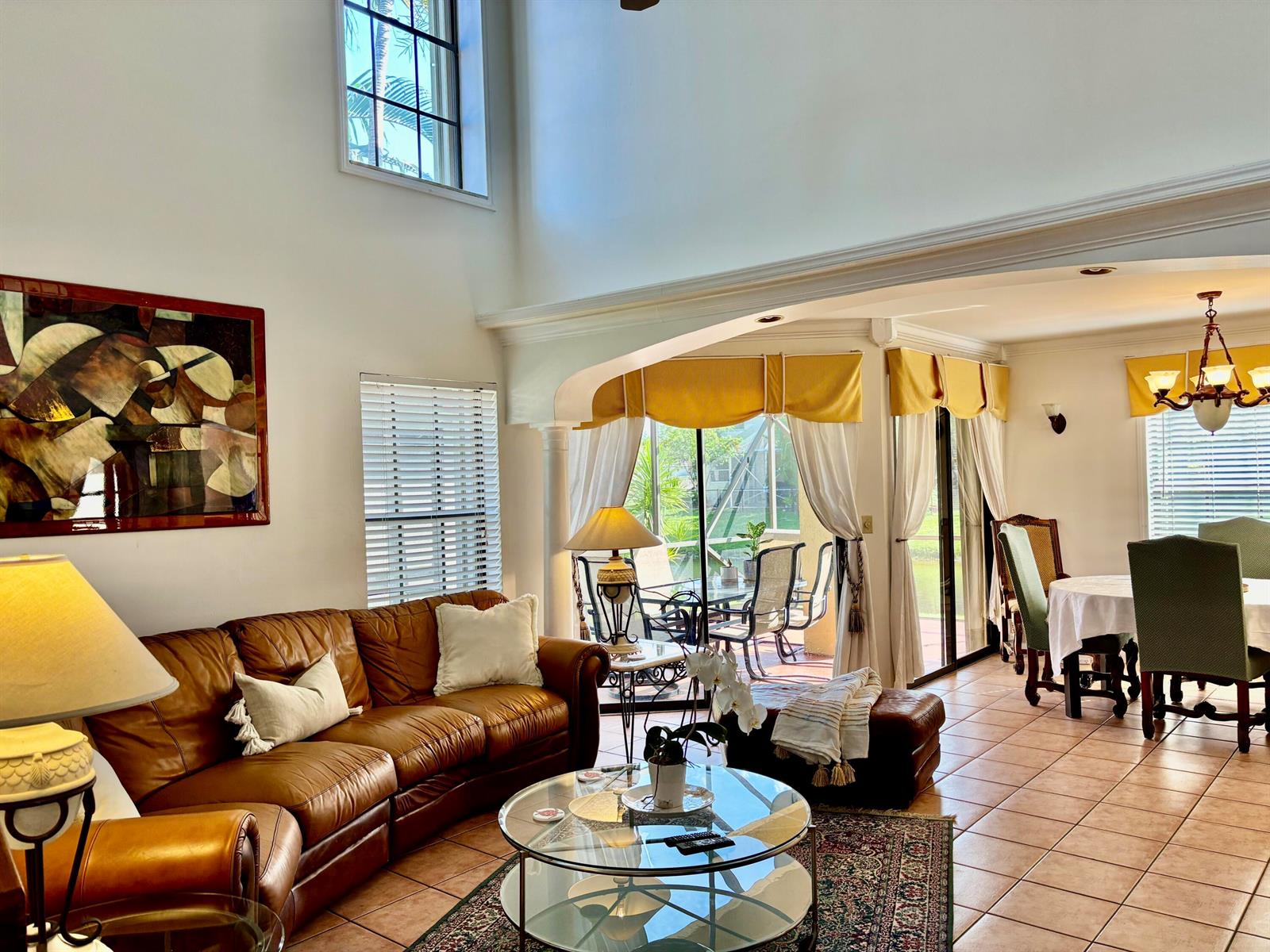 A living room with a leather sofa, glass coffee table, and dining area with tile floors — 1760 Shoreside Circle, Wellington FL 33414, WELLINGTON, FL