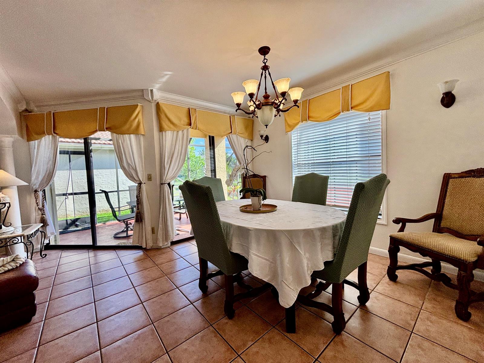 A dining room features a round table, green chairs, tile floors, and sliding glass doors — 1760 Shoreside Circle, Wellington FL 33414, WELLINGTON, FL