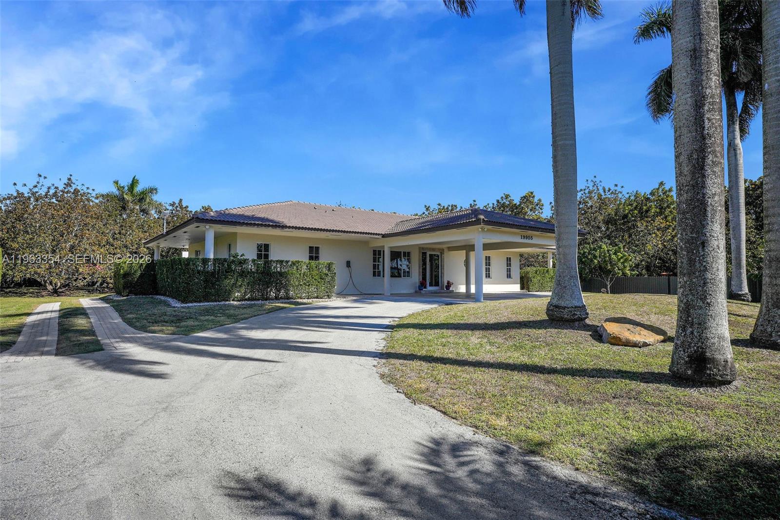 A single-story house with a paved driveway, a covered entryway, and palm trees — 19955 SW 186th St, Miami FL 33187, MIAMI, FL