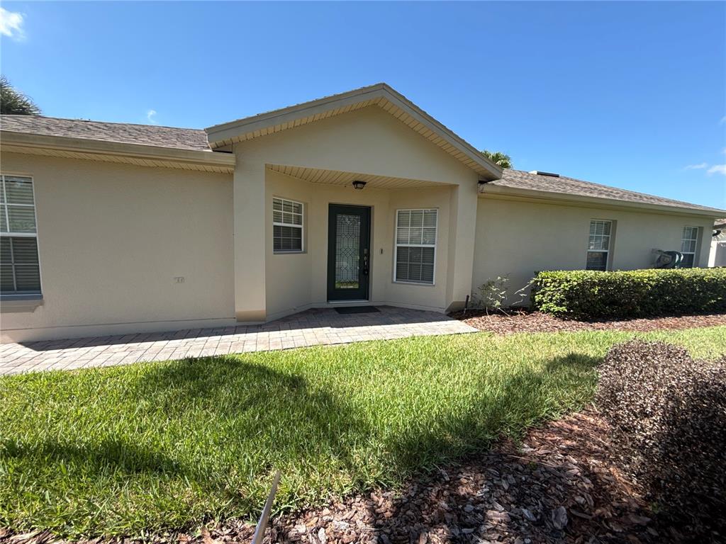 The exterior of a single-story house features a paved walkway leading to a front entrance — 674 VINEYARD WAY, POINCIANA, FL