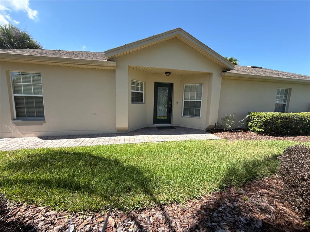 The exterior of a beige single-story house features a paved walkway and a front entrance — 674 VINEYARD WAY, POINCIANA, FL