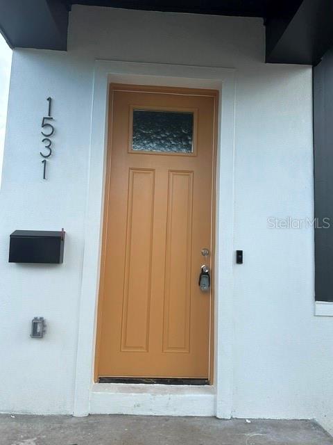 A tan front door with a small window is set into a white exterior wall — 1531 29TH AVENUE N, ST PETERSBURG, FL