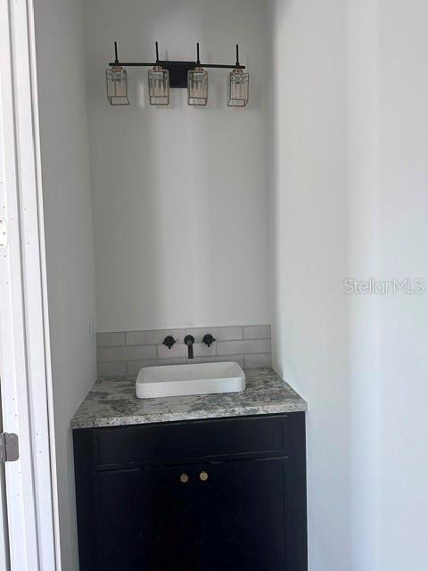 A bathroom vanity features a black cabinet, granite countertop, vessel sink, and modern light fixture — 1531 29TH AVENUE N, ST PETERSBURG, FL