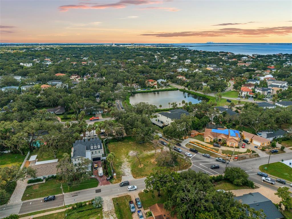 An aerial view shows a residential neighborhood with a central pond and coastal horizon — 2502 S WEST SHORE BOULEVARD, TAMPA, FL
