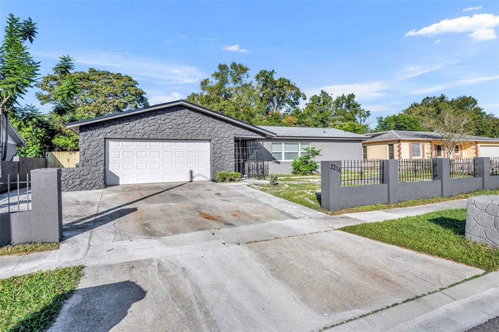 A single-story house with a gray stone facade, a two-car garage, and a fenced yard — 2216 CHERBOURG COURT, ORLANDO, FL