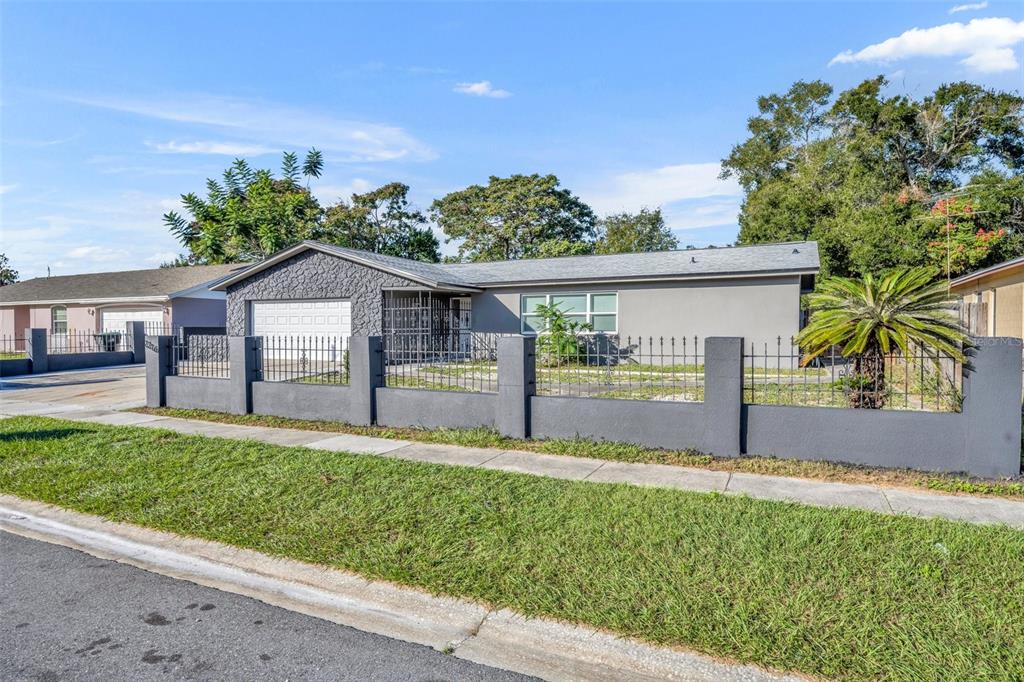 A single-story house with a gray exterior, stone-accented garage, and a gated front yard — 2216 CHERBOURG COURT, ORLANDO, FL