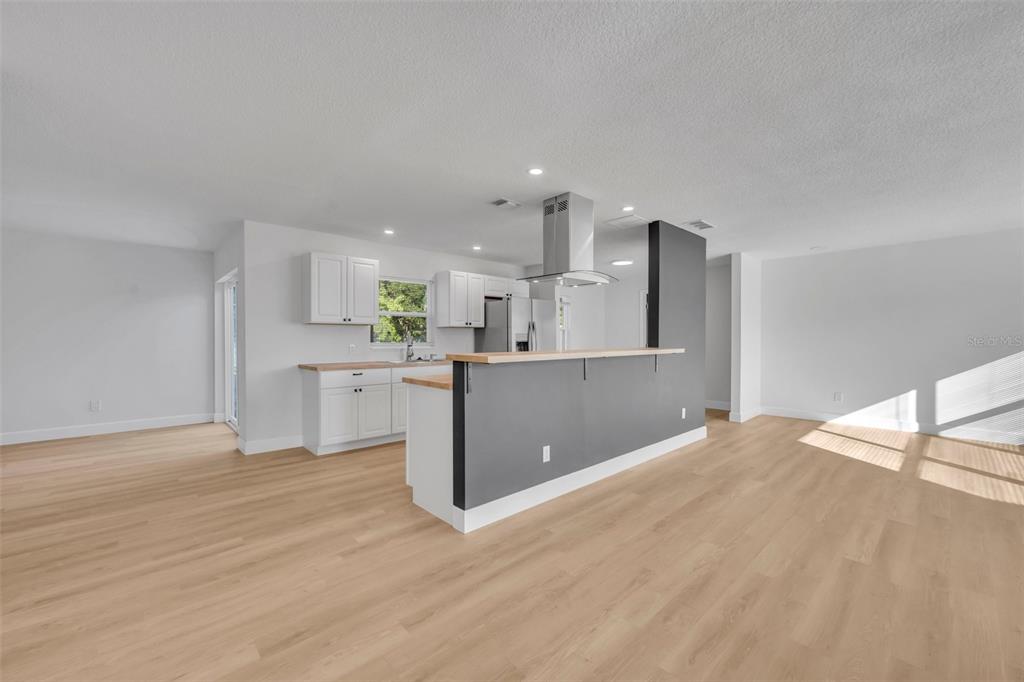 A kitchen with white cabinets, wood countertops, and a gray island with a range hood — 2216 CHERBOURG COURT, ORLANDO, FL