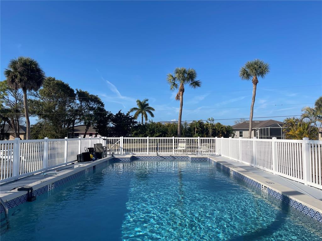 A rectangular swimming pool is enclosed by a white fence under a clear blue sky — 200 ROTONDA BOULEVARD W UNIT A4, ROTONDA WEST, FL