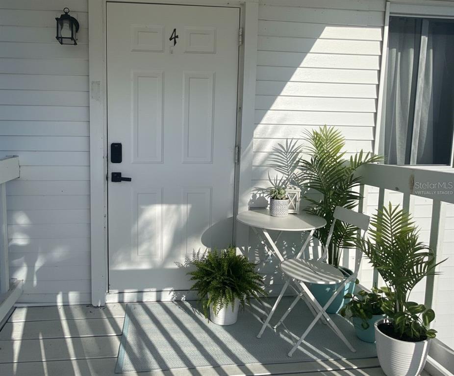 A white front door numbered four opens onto a small porch with a bistro set — 200 ROTONDA BOULEVARD W UNIT A4, ROTONDA WEST, FL