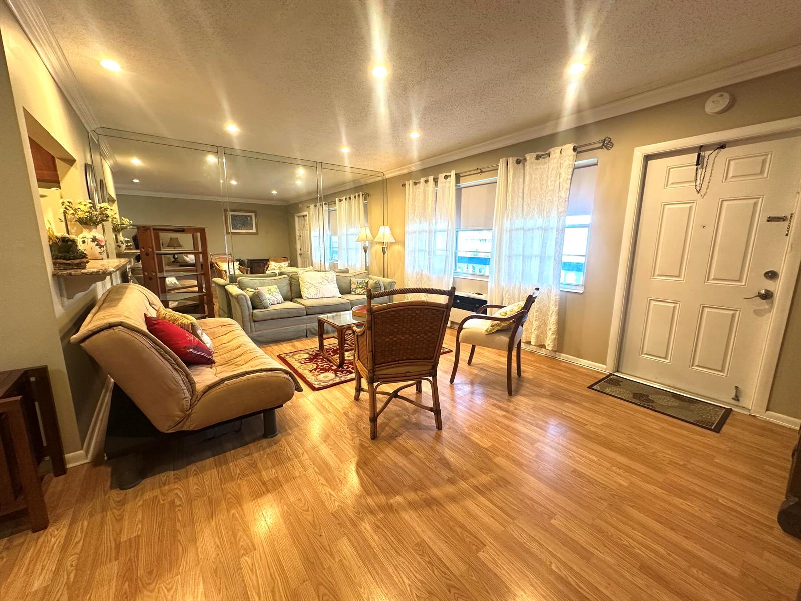 A living room features wood-look flooring, a mirrored wall, a sofa, and a front door — 238 Newport O # 238, Deerfield Beach FL 33442, DEERFIELD BEACH, FL