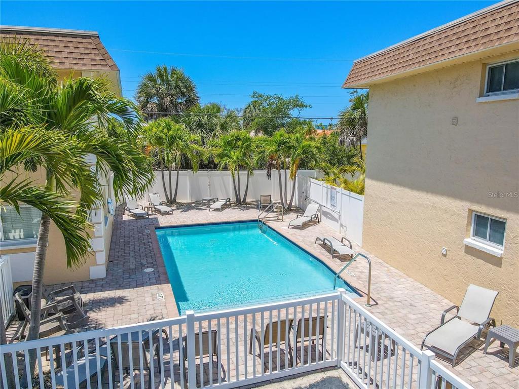 An outdoor swimming pool surrounded by a brick patio, lounge chairs, and palm trees — 9050 BLIND PASS ROAD UNIT 9, ST PETE BEACH, FL
