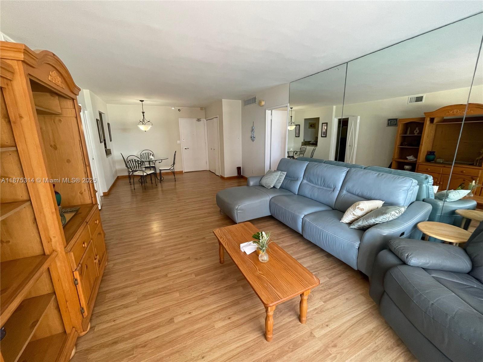 A living room features a blue sectional sofa, a wooden coffee table, and mirrored walls — 5161 Collins Ave # 603, Miami Beach FL 33140, MIAMI BEACH, FL