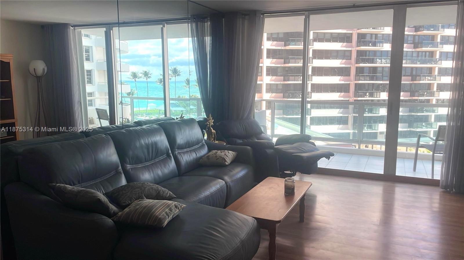 A living room features a dark leather sectional, a wooden coffee table, and balcony views — 5161 Collins Ave # 603, Miami Beach FL 33140, MIAMI BEACH, FL