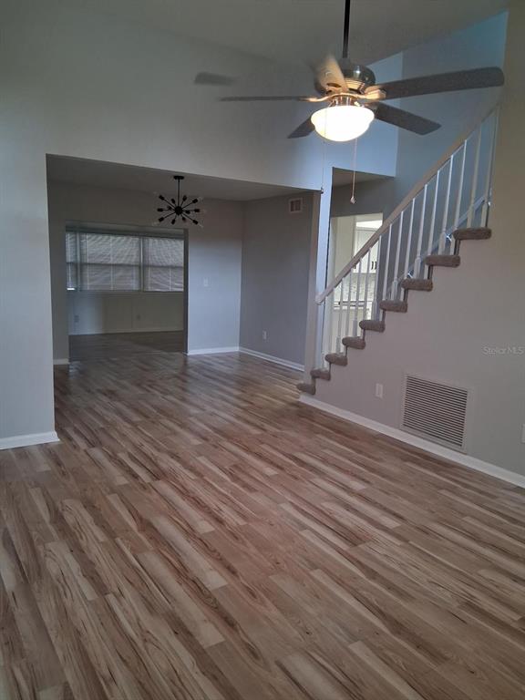 A living room with wood-look flooring, a ceiling fan, and stairs leading to an upper level — 5102 PEACHGREEN COURT, TAMPA, FL