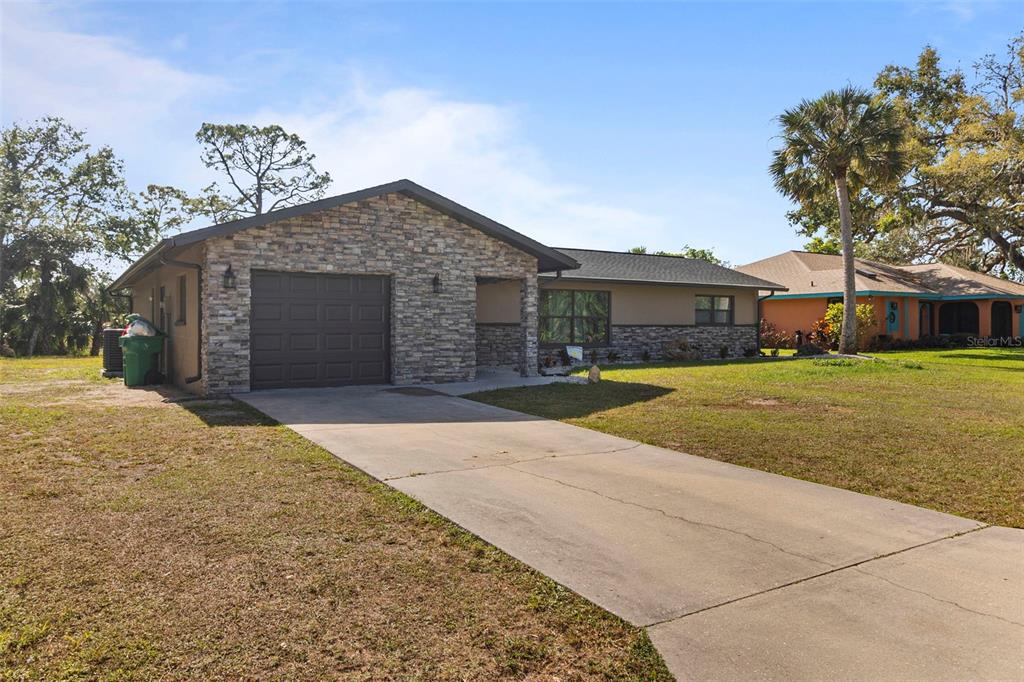 A single-story house with a stone facade, a one-car garage, and a concrete driveway — 20495 ALBURY DRIVE, PORT CHARLOTTE, FL
