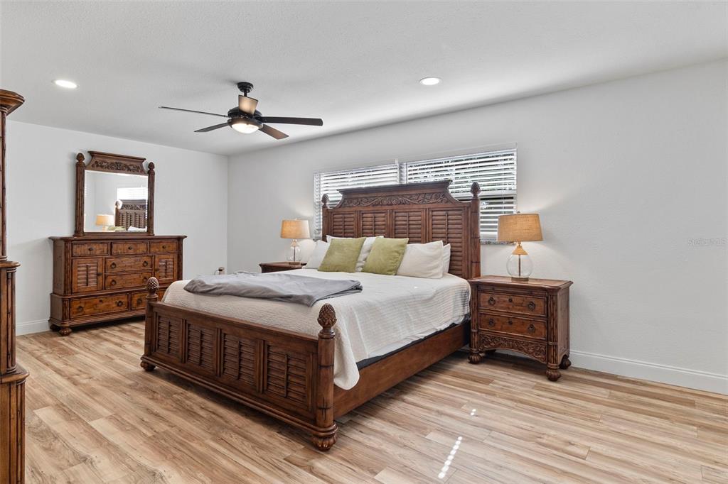 A bedroom features a wooden bed frame, matching dresser, and light wood-look flooring — 20495 ALBURY DRIVE, PORT CHARLOTTE, FL