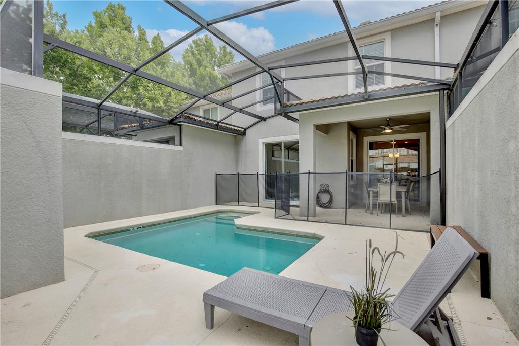 A screened-in patio features a small swimming pool, a safety fence, and a lounge chair — 3062 GATSBY STREET, KISSIMMEE, FL