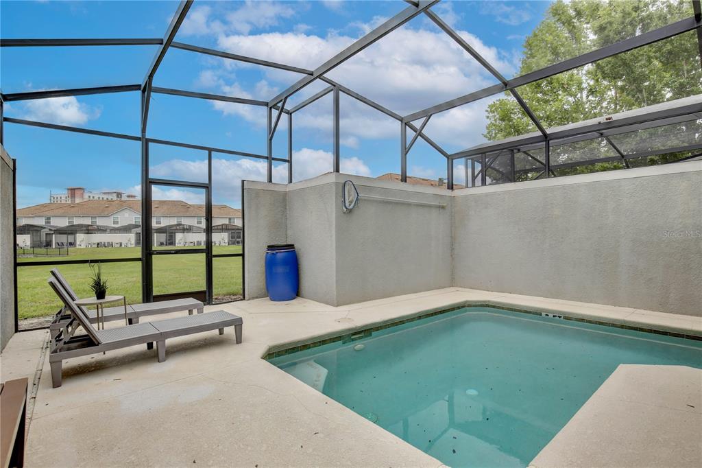 A screened-in patio features a small rectangular swimming pool, two lounge chairs, and a blue barrel — 3062 GATSBY STREET, KISSIMMEE, FL