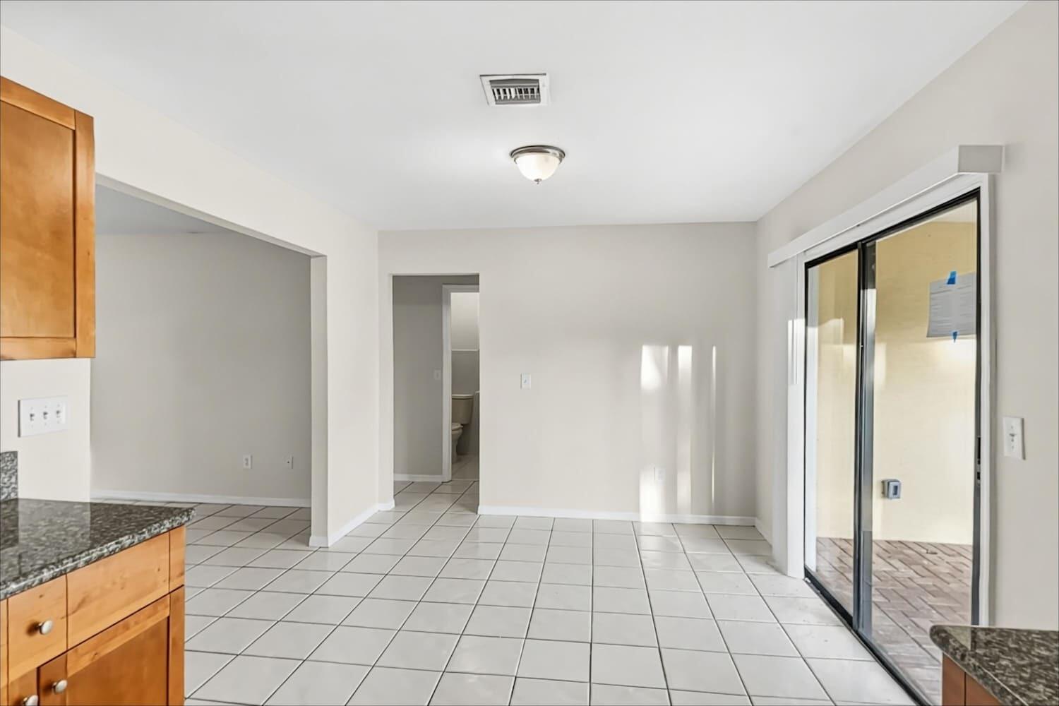 A dining area with white tile floors, light walls, and a sliding glass door — NORTH PALM BEACH, FL