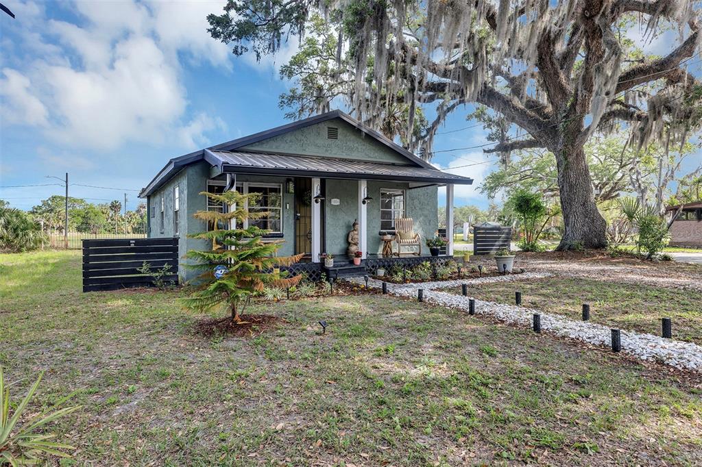 A green, single-story house with a front porch sits under a large, moss-draped oak tree — 1806 REDDING PLACE, SANFORD, FL