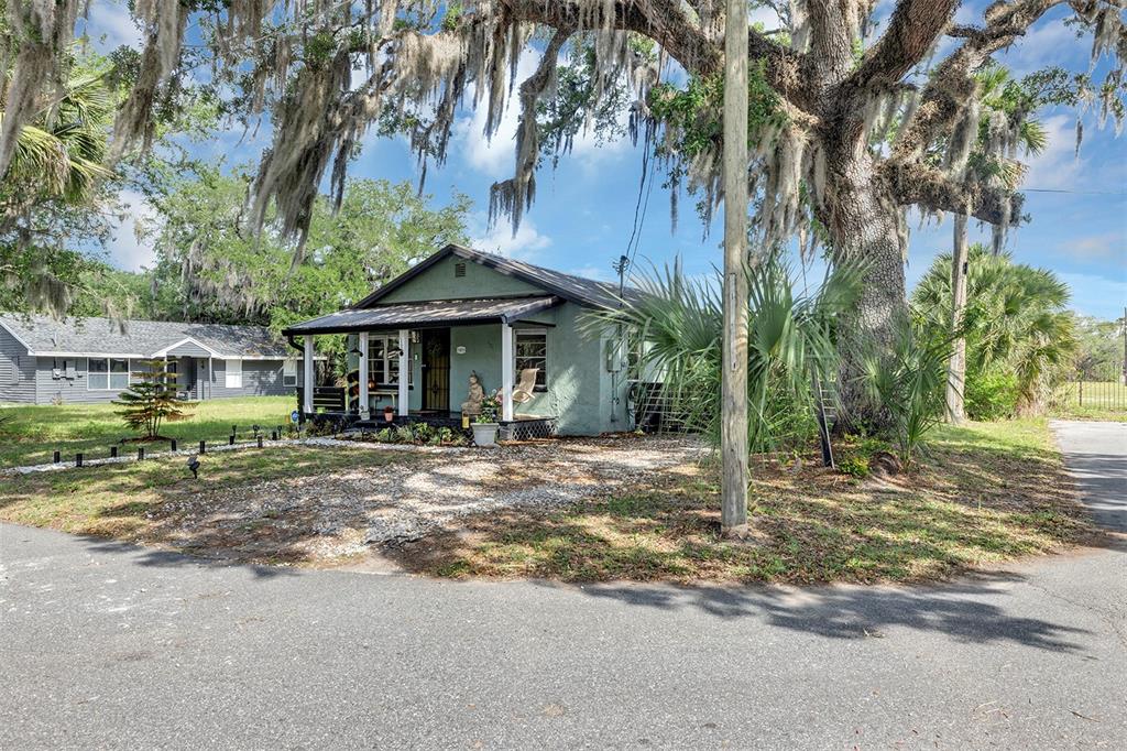 A green single-story house with a front porch sits under a large moss-covered oak tree — 1806 REDDING PLACE, SANFORD, FL