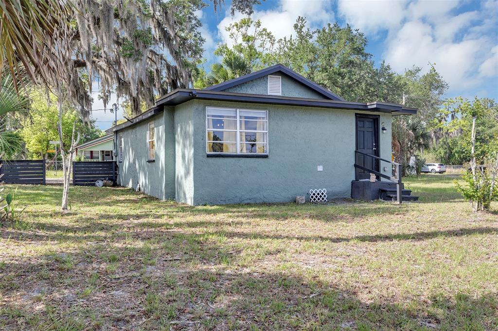 A single-story green house with a dark door and window frames sits on a lawn — 1806 REDDING PLACE, SANFORD, FL