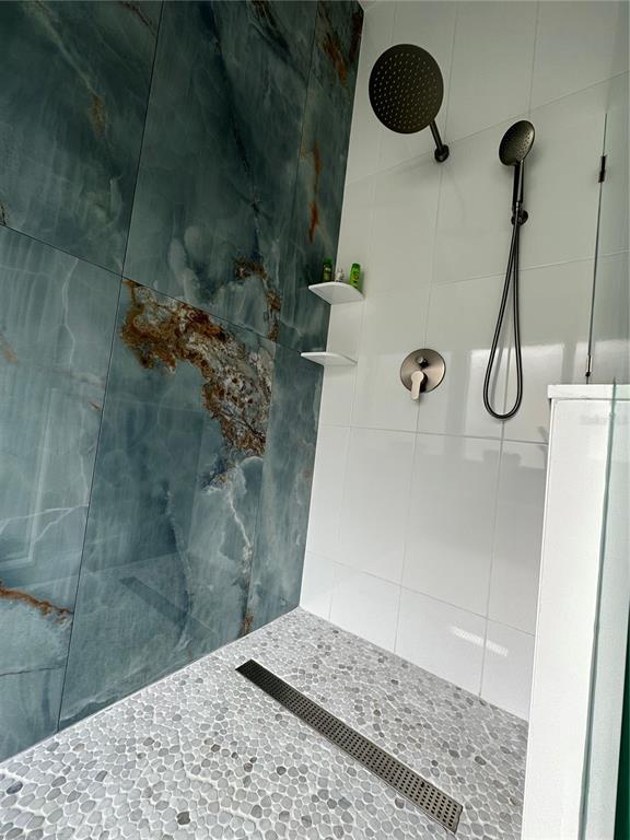 A walk-in shower features blue marble-look wall tiles, white subway tiles, and a pebble floor — 29651 BIRDS EYE DRIVE, WESLEY CHAPEL, FL