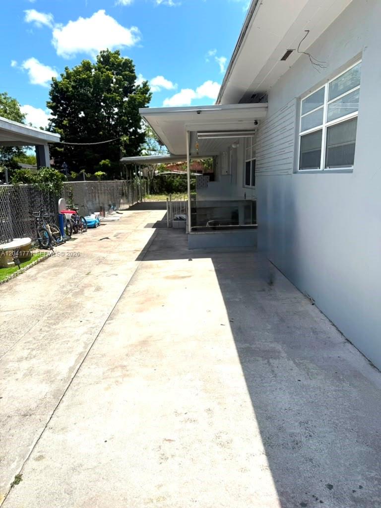 A concrete driveway runs alongside the exterior wall of a house with a covered patio — 42 E 13th St, Hialeah FL 33010, HIALEAH, FL
