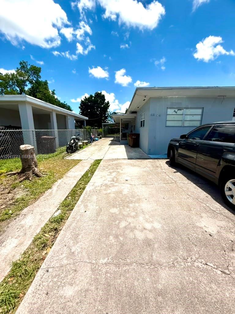 A concrete driveway leads alongside a light blue house with a covered side entrance — 42 E 13th St, Hialeah FL 33010, HIALEAH, FL