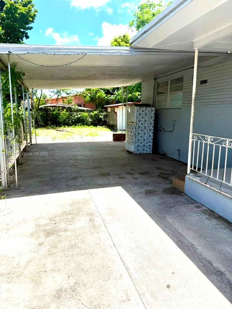 A concrete carport area features a covered roof, a refrigerator, and a metal railing — 42 E 13th St, Hialeah FL 33010, HIALEAH, FL