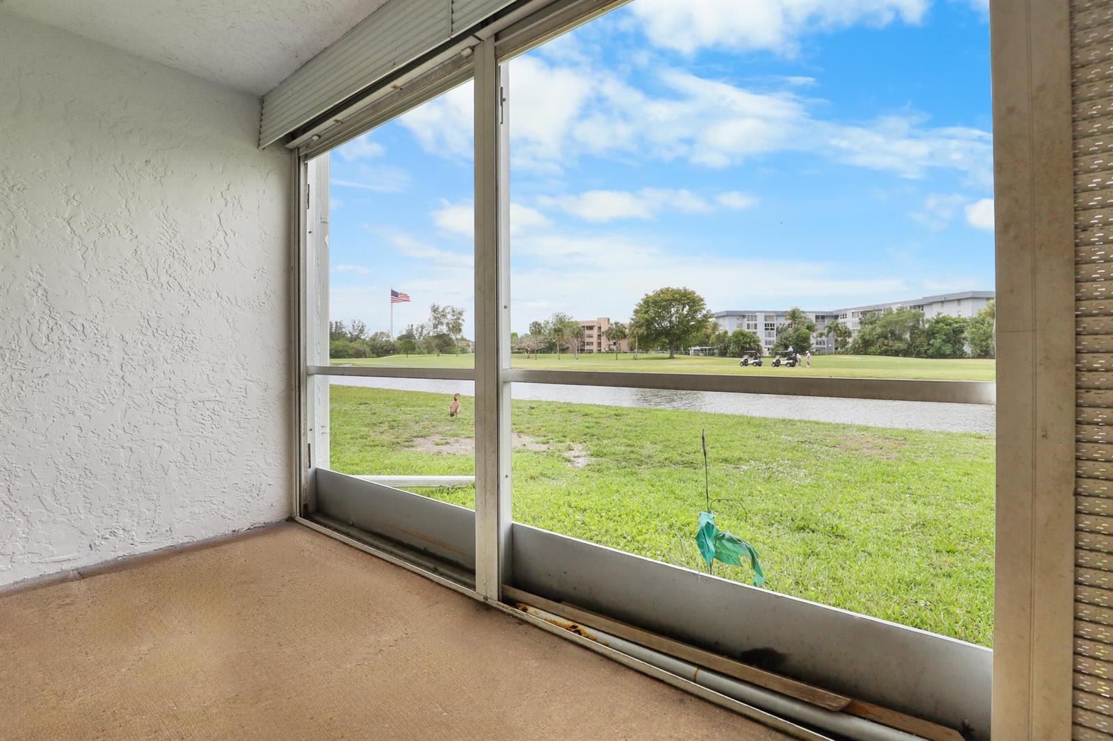 A screened-in porch overlooks a grassy lawn, a small pond, and a golf course — 1460 NW 80th Avenue # 108, Margate FL 33063, MARGATE, FL
