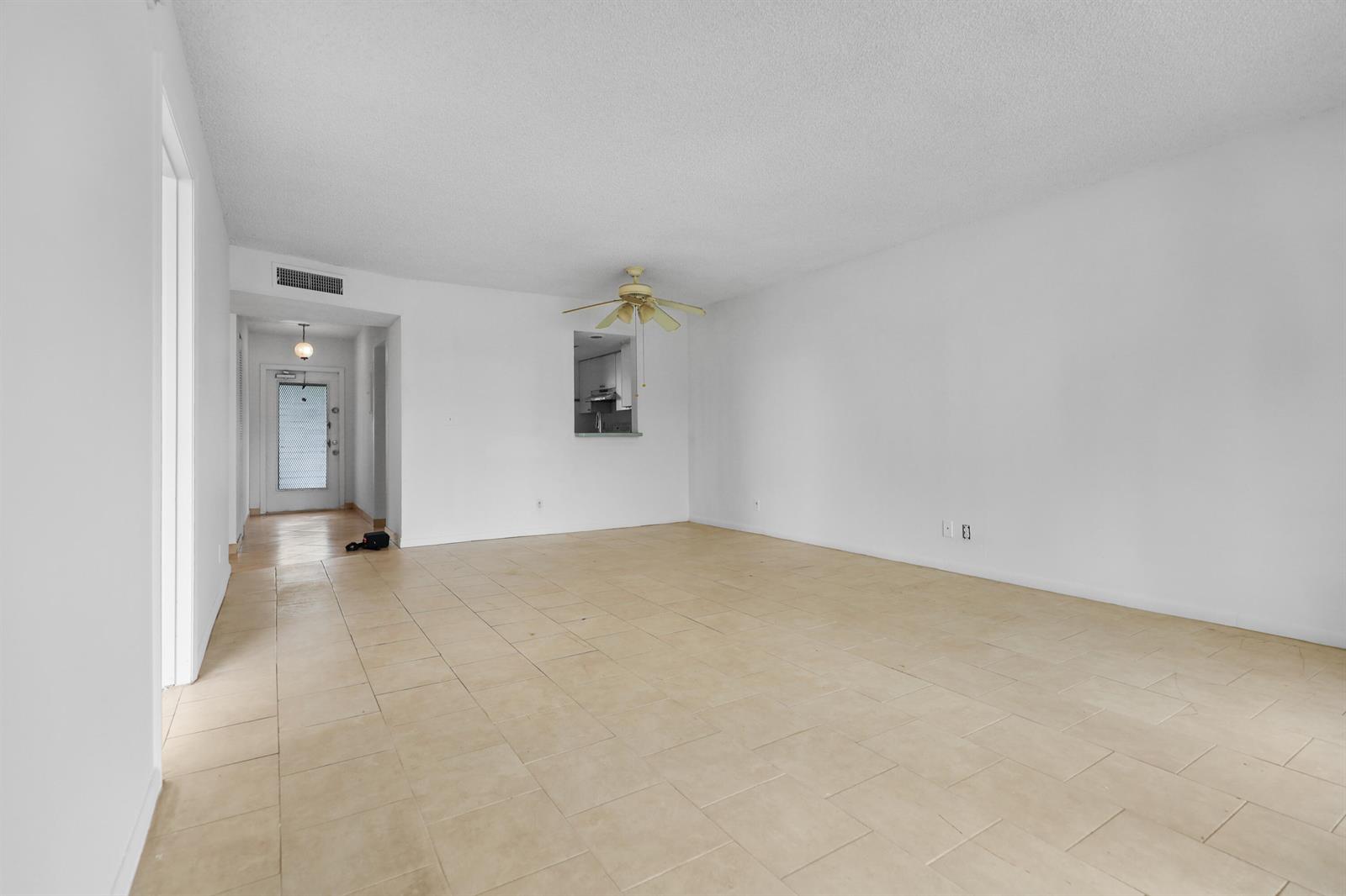 An empty living room features beige tile flooring, white walls, and a ceiling fan — 1460 NW 80th Avenue # 108, Margate FL 33063, MARGATE, FL