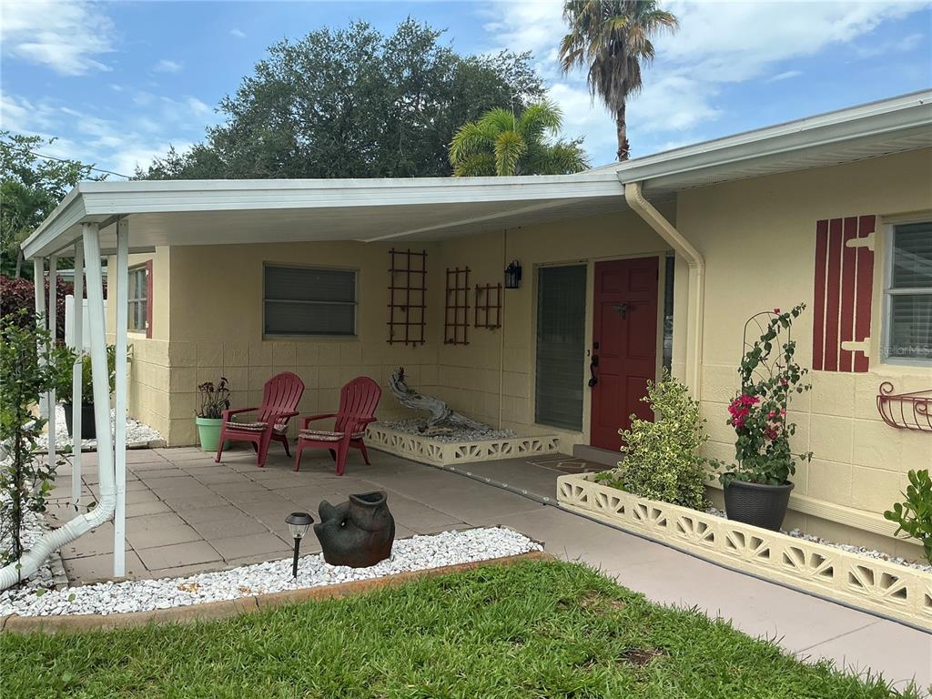 A covered patio with a concrete floor sits in front of a house with yellow siding — 7360 111TH STREET, SEMINOLE, FL