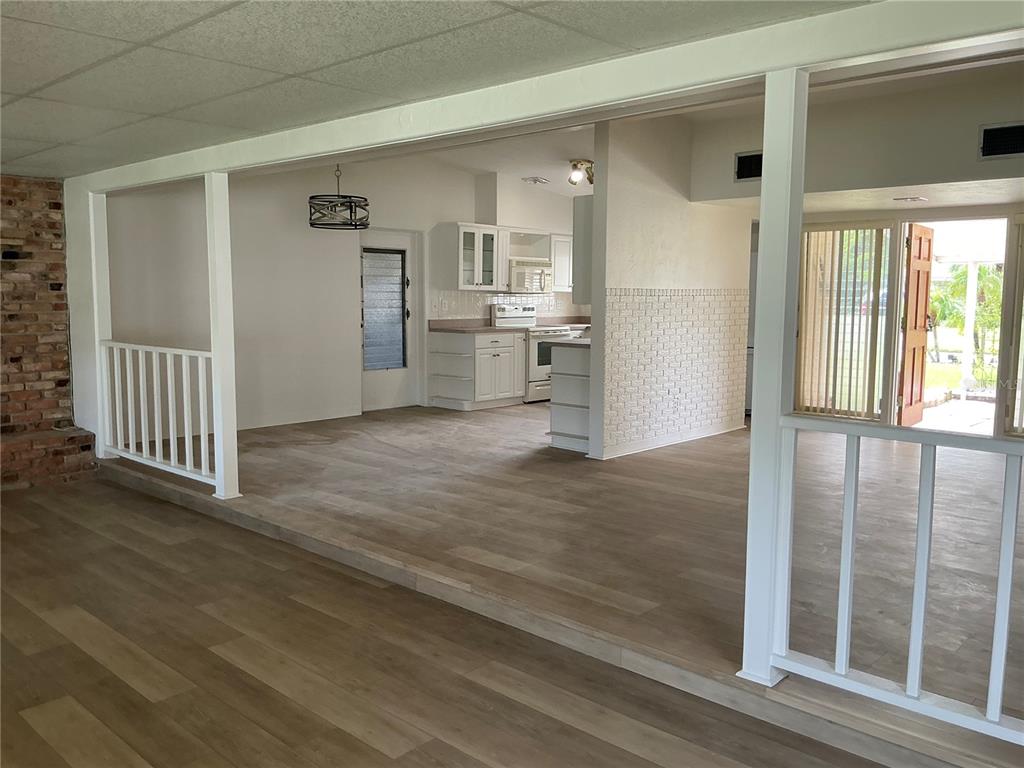 An open-concept living area features a sunken floor, white railings, and a kitchen with white cabinets — 7360 111TH STREET, SEMINOLE, FL