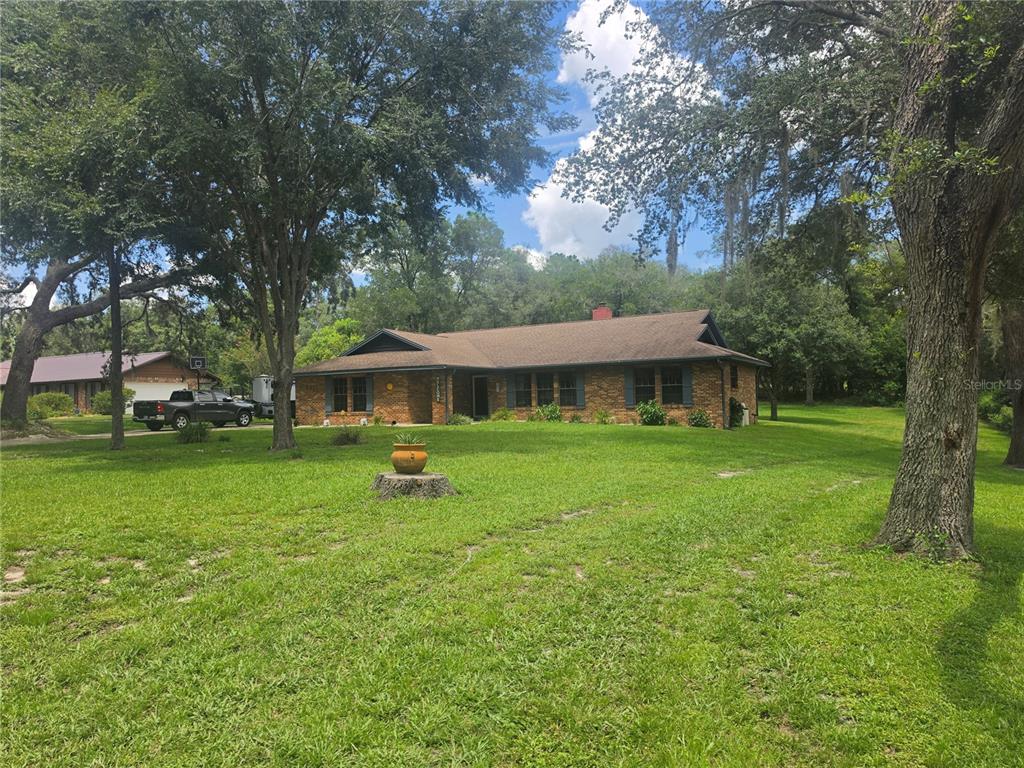 A single-story brick house with a brown roof sits on a large, grassy lot — 2417 S OAK PARK DRIVE, DELAND, FL