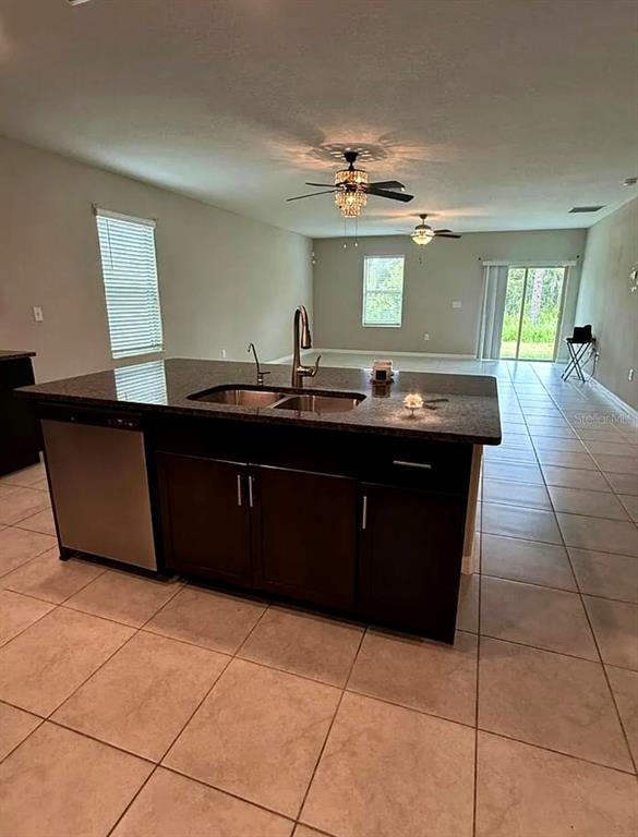 A kitchen island with a dark cabinet base and granite countertop sits in an open-concept room — 12957 WILDFLOWER MEADOW DRIVE, RIVERVIEW, FL