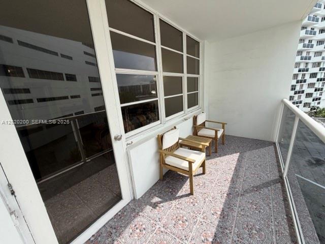 A balcony features tiled flooring, two wooden chairs with cushions, and a glass railing — 3725 S Ocean Dr # 615, Hollywood FL 33019, HOLLYWOOD, FL