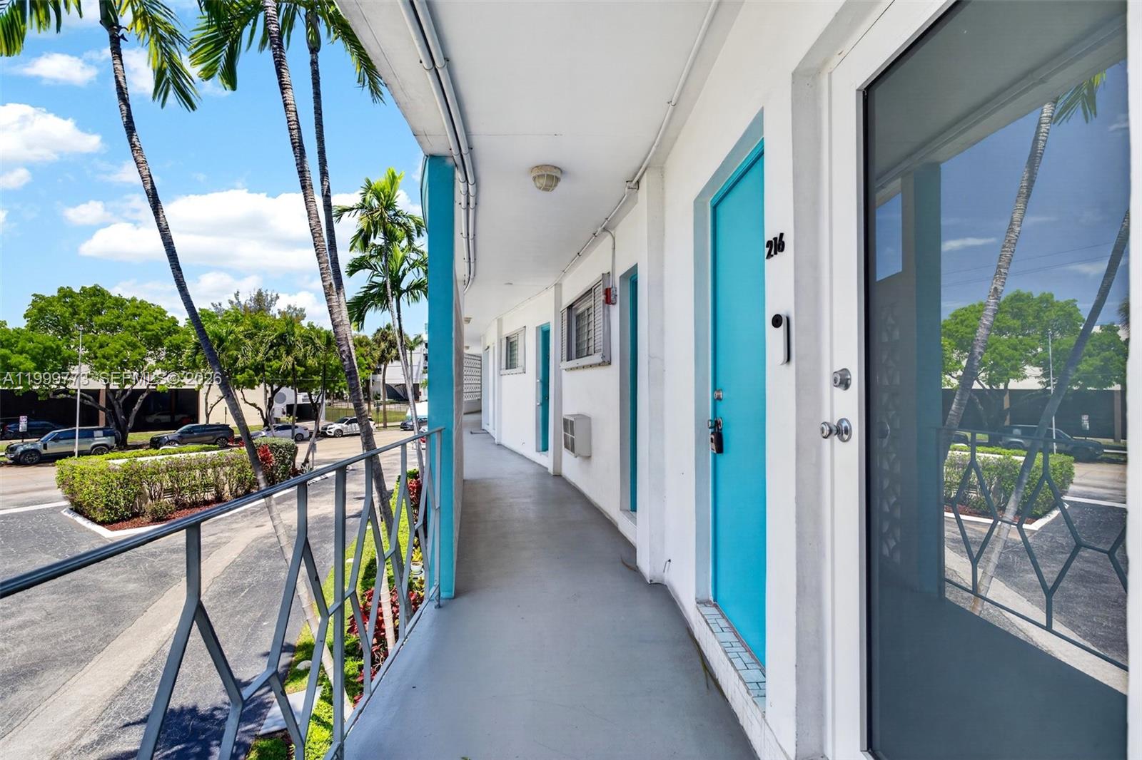 An outdoor walkway with blue doors leads past apartment units under a covered roof — 2500 Diana Dr # 216, Hallandale Beach FL 33009, HALLANDALE BEACH, FL