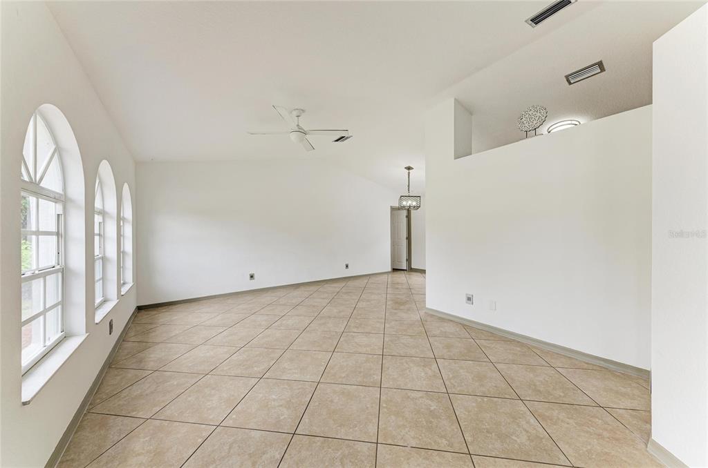 An empty room with beige tile flooring, white walls, arched windows, and a ceiling fan — 3081 JODY STREET, PORT CHARLOTTE, FL
