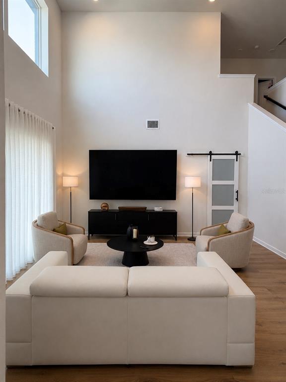 A living room features a large television, a white sofa, two armchairs, and a sliding door — 17152 CERCIS LOOP, CLERMONT, FL