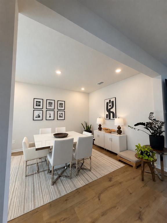 A dining room features a white table, six chairs, a sideboard, and framed wall art — 17152 CERCIS LOOP, CLERMONT, FL