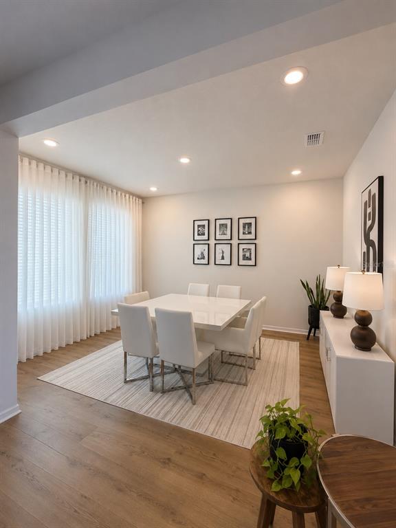 A dining room features a white square table, six white chairs, and a striped area rug — 17152 CERCIS LOOP, CLERMONT, FL