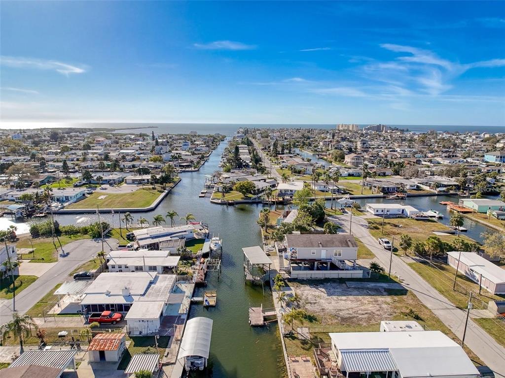 An aerial view of a residential canal neighborhood leading toward the open ocean — 6736 CURLEW LANE, HUDSON, FL