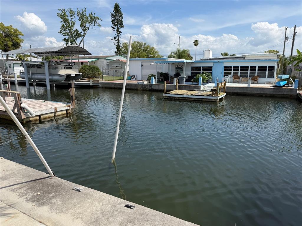 A canal view shows a boat lift, a floating dock, and a waterfront mobile home — 6736 CURLEW LANE, HUDSON, FL