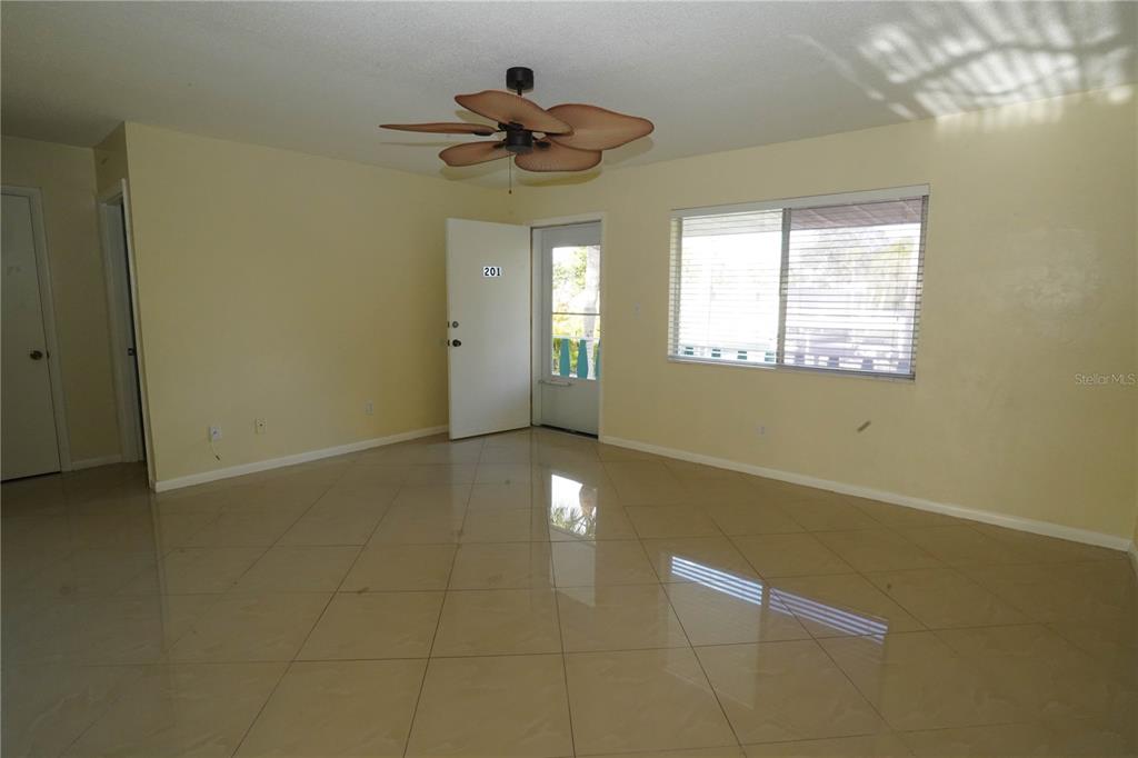 An empty room features light-colored tile flooring, pale yellow walls, and a ceiling fan — 349 JOEL BOULEVARD UNIT 201, LEHIGH ACRES, FL