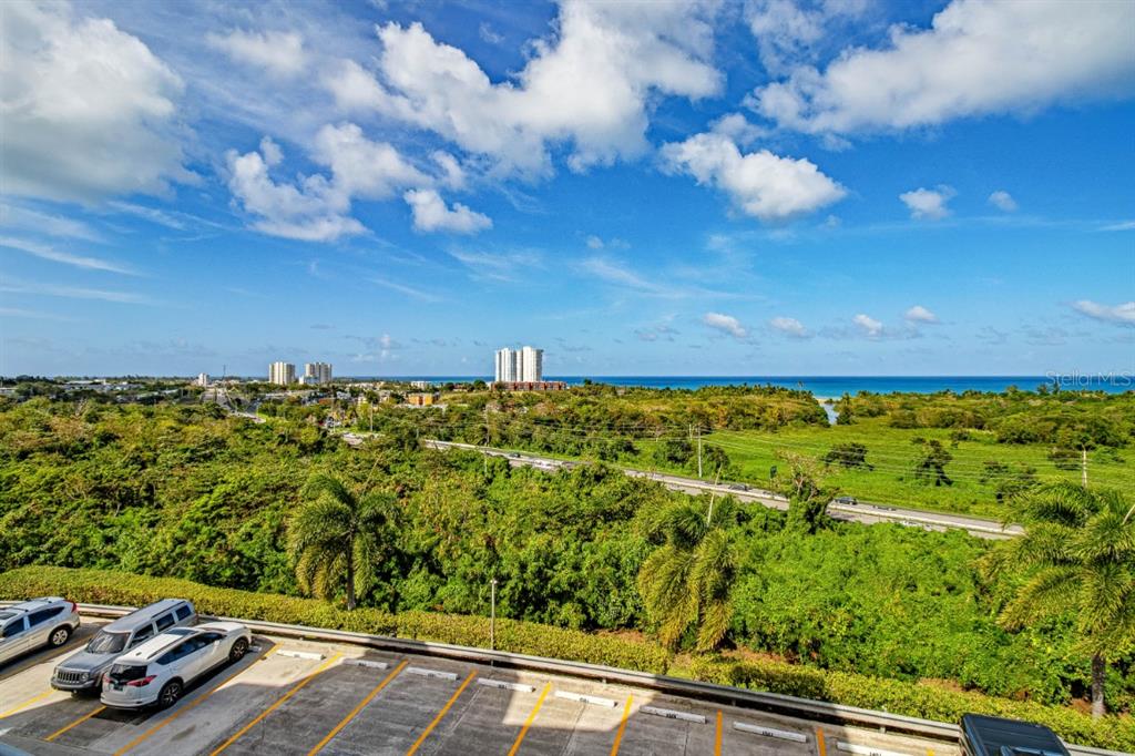 An elevated view of a parking lot overlooking a lush green landscape and the ocean — 100 OCEAN PLAZA DRIVE UNIT 15, LUQUILLO, PR