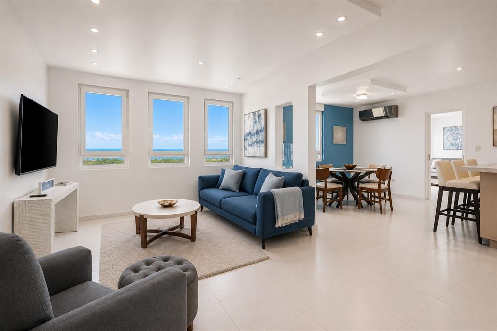 A bright living room features a blue sofa, a round coffee table, and ocean views — 100 OCEAN PLAZA DRIVE UNIT 15, LUQUILLO, PR